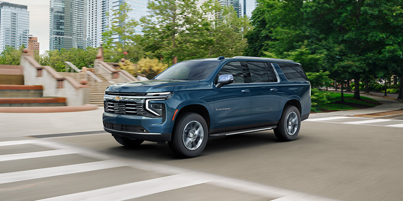 Blue SUV driving through a city street.